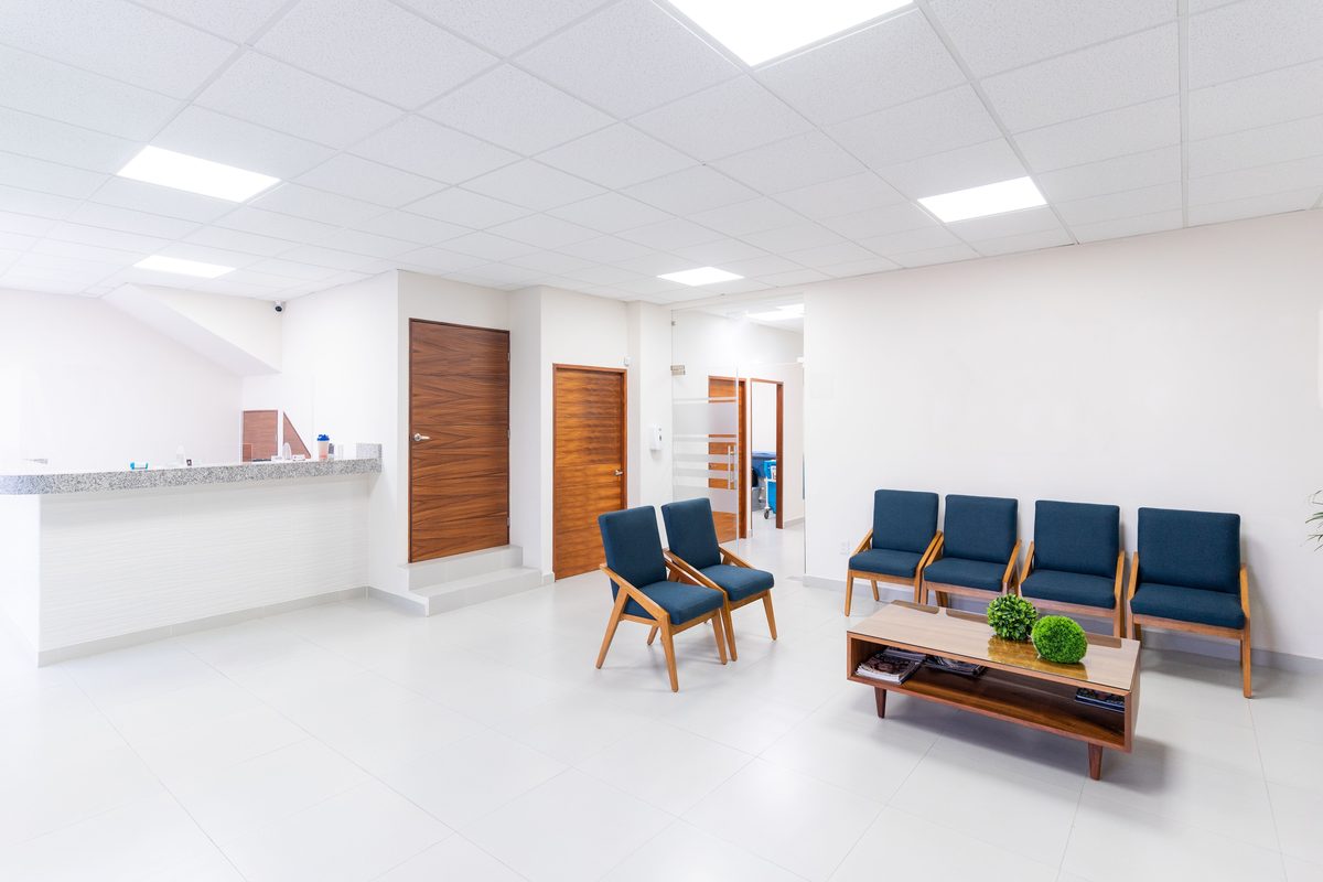 An empty, bright clinic waiting area with navy chairs and a wood coffee table